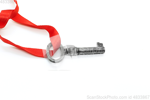 Image of Vintage silver key with red ribbon on white background