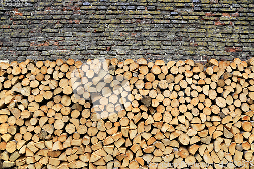 Image of Stack of firewood against old weathered brick wall