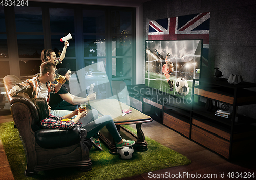 Image of Group of friends watching TV, football match in Great Britain, sport games