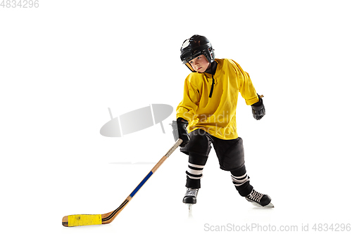 Image of Little hockey player with the stick on ice court and white studio background