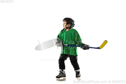 Image of Little hockey player with the stick on ice court and white studio background