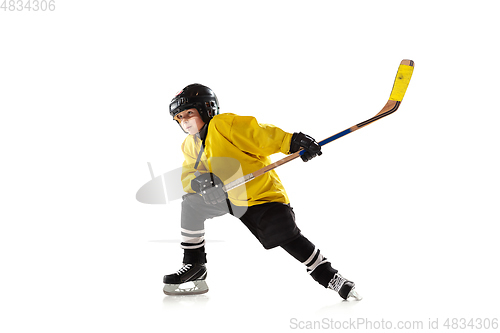 Image of Little hockey player with the stick on ice court and white studio background