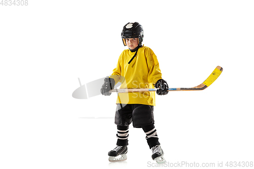 Image of Little hockey player with the stick on ice court and white studio background