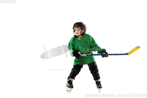 Image of Little hockey player with the stick on ice court and white studio background