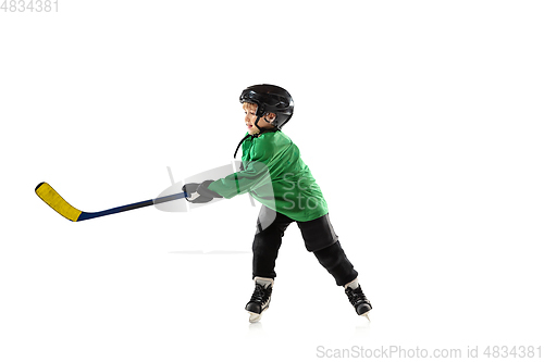 Image of Little hockey player with the stick on ice court and white studio background