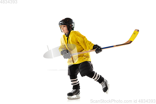 Image of Little hockey player with the stick on ice court and white studio background