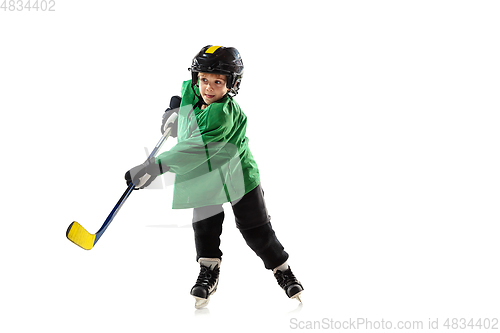 Image of Little hockey player with the stick on ice court and white studio background