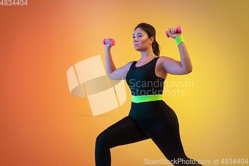 Image of Young caucasian plus size female model\'s training on gradient orange background