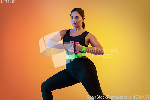 Image of Young caucasian plus size female model\'s training on gradient orange background