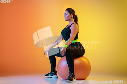 Image of Young caucasian plus size female model\'s training on gradient orange background
