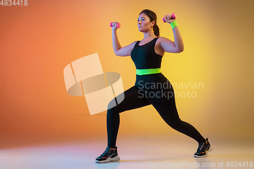 Image of Young caucasian plus size female model\'s training on gradient orange background