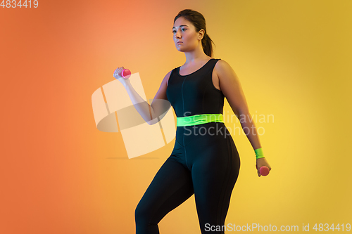 Image of Young caucasian plus size female model\'s training on gradient orange background