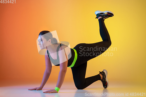 Image of Young caucasian plus size female model\'s training on gradient orange background