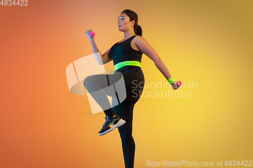 Image of Young caucasian plus size female model\'s training on gradient orange background