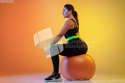 Image of Young caucasian plus size female model\'s training on gradient orange background