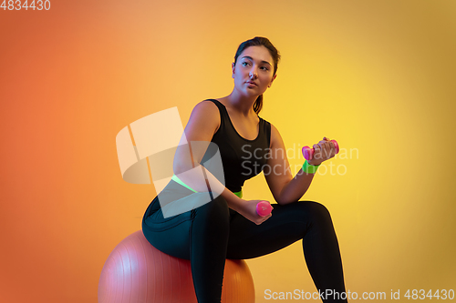 Image of Young caucasian plus size female model\'s training on gradient orange background
