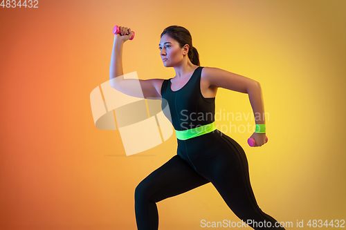 Image of Young caucasian plus size female model\'s training on gradient orange background