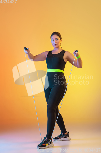 Image of Young caucasian plus size female model\'s training on gradient orange background