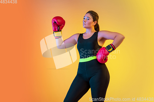 Image of Young caucasian plus size female model\'s training on gradient orange background