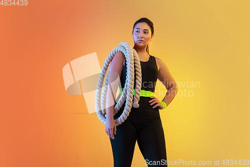 Image of Young caucasian plus size female model\'s training on gradient orange background