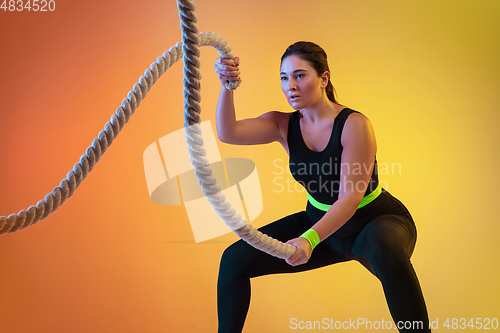 Image of Young caucasian plus size female model\'s training on gradient orange background