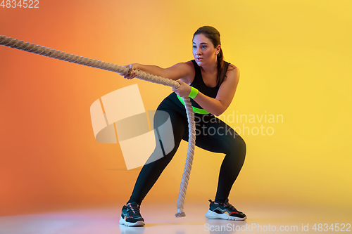 Image of Young caucasian plus size female model\'s training on gradient orange background