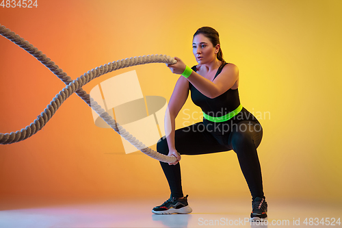 Image of Young caucasian plus size female model\'s training on gradient orange background