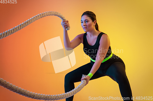 Image of Young caucasian plus size female model\'s training on gradient orange background