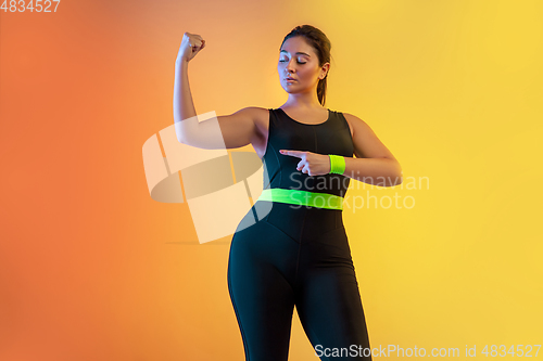 Image of Young caucasian plus size female model\'s training on gradient orange background