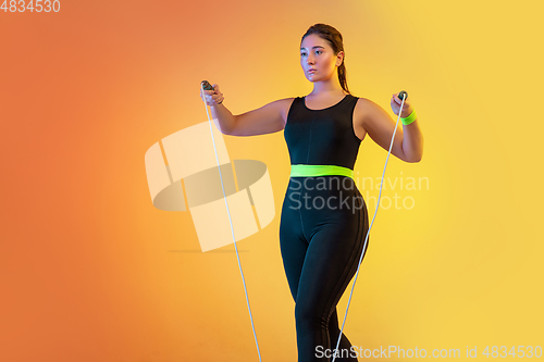 Image of Young caucasian plus size female model\'s training on gradient orange background