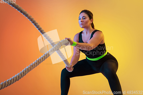 Image of Young caucasian plus size female model\'s training on gradient orange background