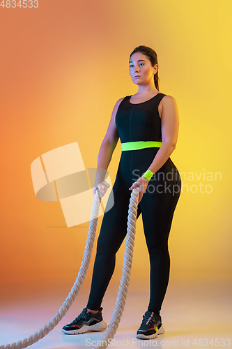 Image of Young caucasian plus size female model\'s training on gradient orange background