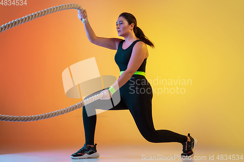 Image of Young caucasian plus size female model\'s training on gradient orange background