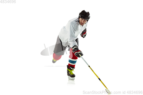 Image of Young male hockey player with the stick on ice court and white background