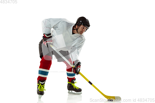 Image of Young male hockey player with the stick on ice court and white background