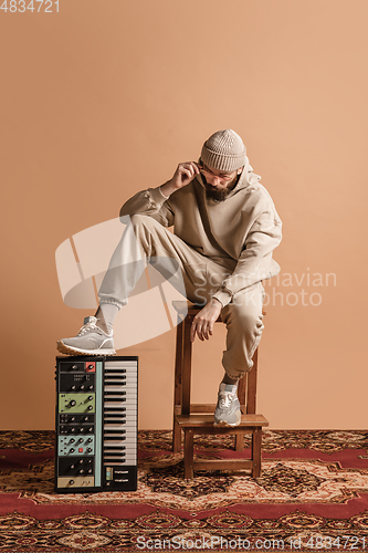 Image of Full-length portrait of man, musician isolated on light yellow background.