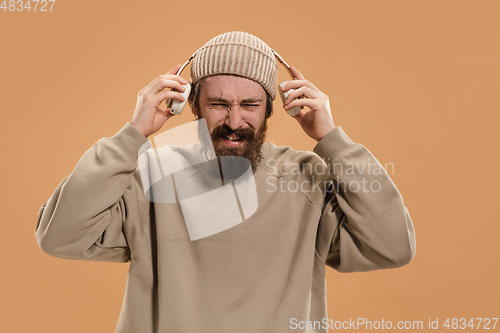 Image of Portrait of Caucasian man in headphones and hat isolated on light background.