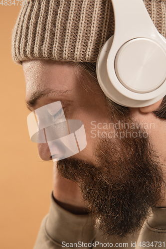 Image of Close-up Caucasian man in headphones and hat isolated on light background.