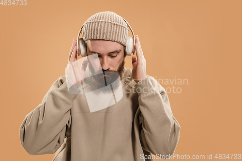 Image of Portrait of Caucasian man in headphones and hat isolated on light background.