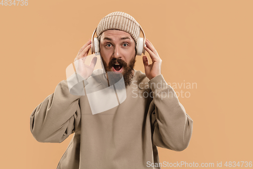 Image of Portrait of Caucasian man in headphones and hat isolated on light background.