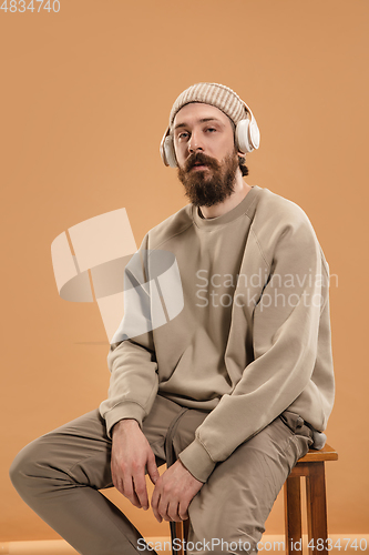 Image of Portrait of Caucasian man in headphones and hat isolated on light background.