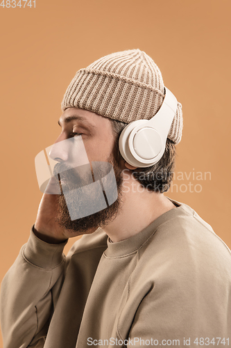 Image of Portrait of Caucasian man in headphones and hat isolated on light background.