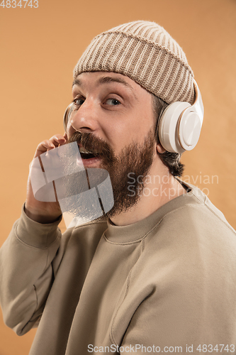 Image of Portrait of Caucasian man in headphones and hat isolated on light background.