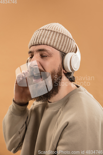 Image of Portrait of Caucasian man in headphones and hat isolated on light background.