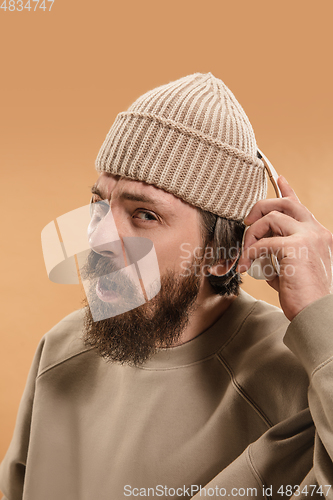 Image of Portrait of Caucasian man in headphones and hat isolated on light background.