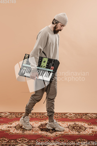 Image of Full-length portrait of man, musician isolated on light yellow background.
