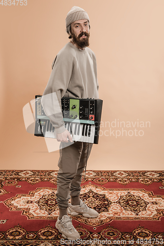 Image of Full-length portrait of man, musician isolated on light yellow background.