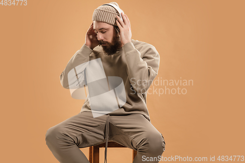 Image of Portrait of Caucasian man in headphones and hat isolated on light background.