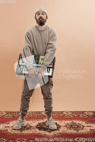 Image of Full-length portrait of man, musician isolated on light yellow background.