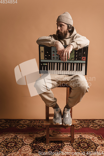 Image of Full-length portrait of man, musician isolated on light yellow background.